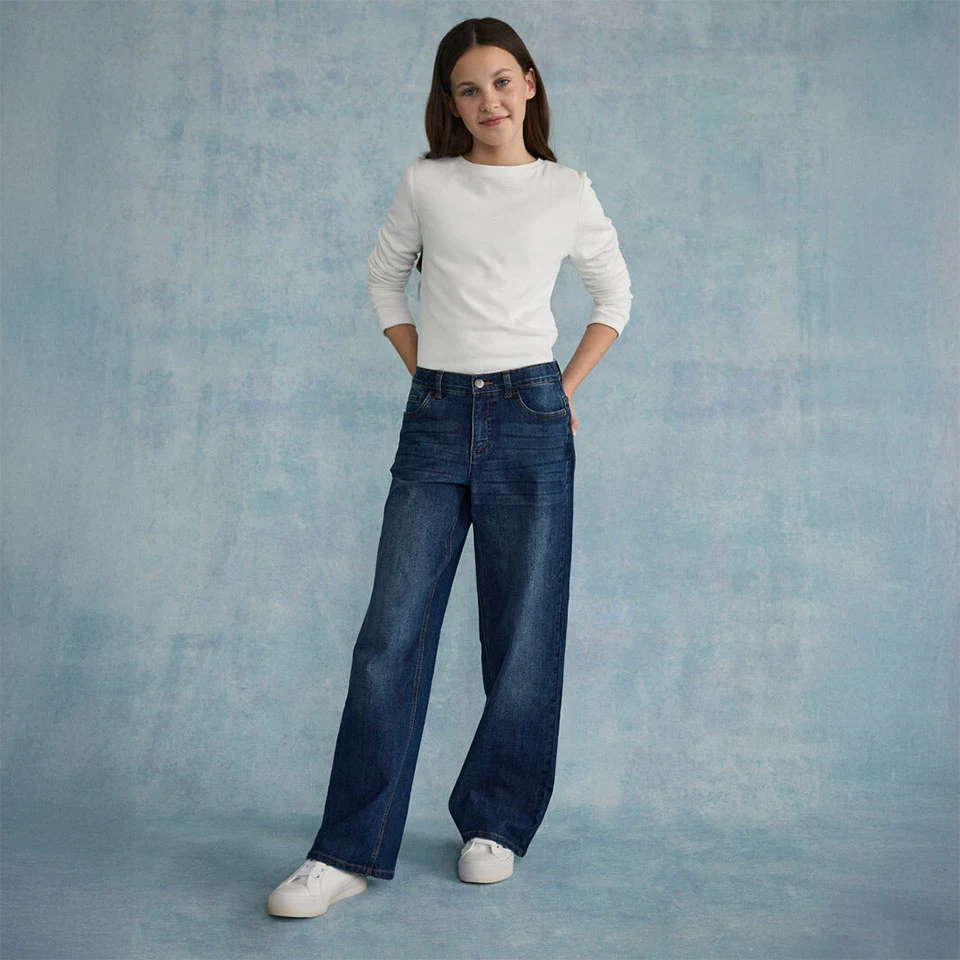 Bílý strukturovaný top v kombinaci s širokými džínami a bílými teniskami.