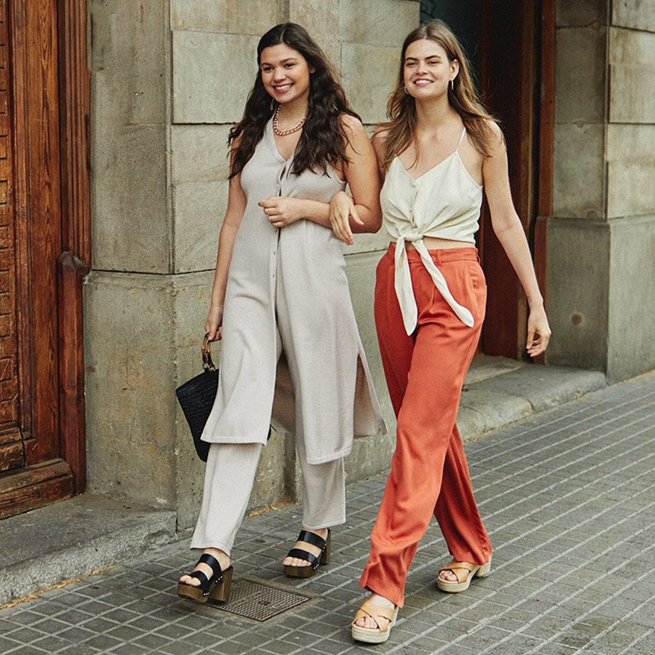 Letní elegance: světlé kalhotové kostýmky a splývavé topy v kombinaci s oranžovými kalhotami a espadrilkami.
