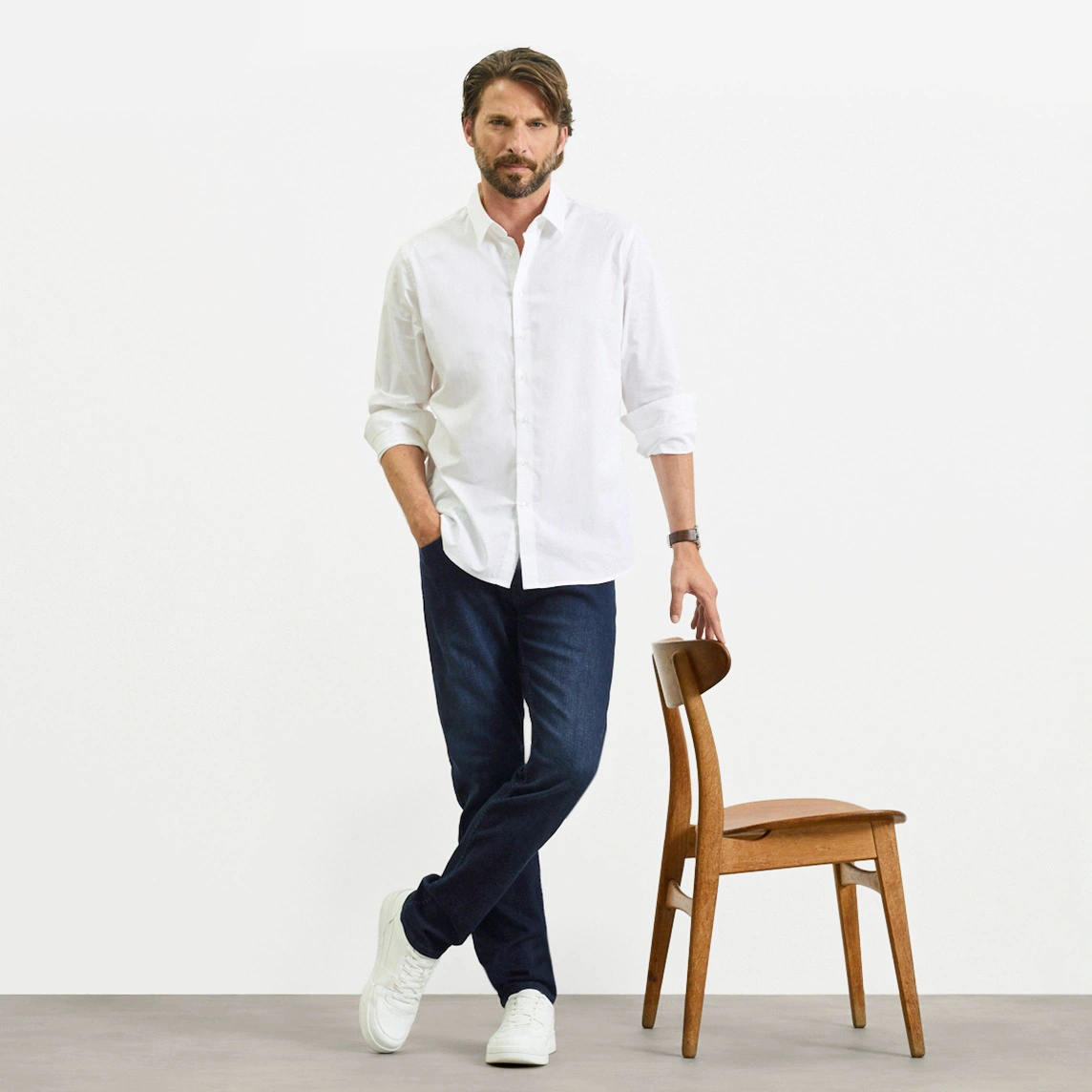 Bílá košile, tmavé džíny střihu Slim Fit a bílé tenisky.