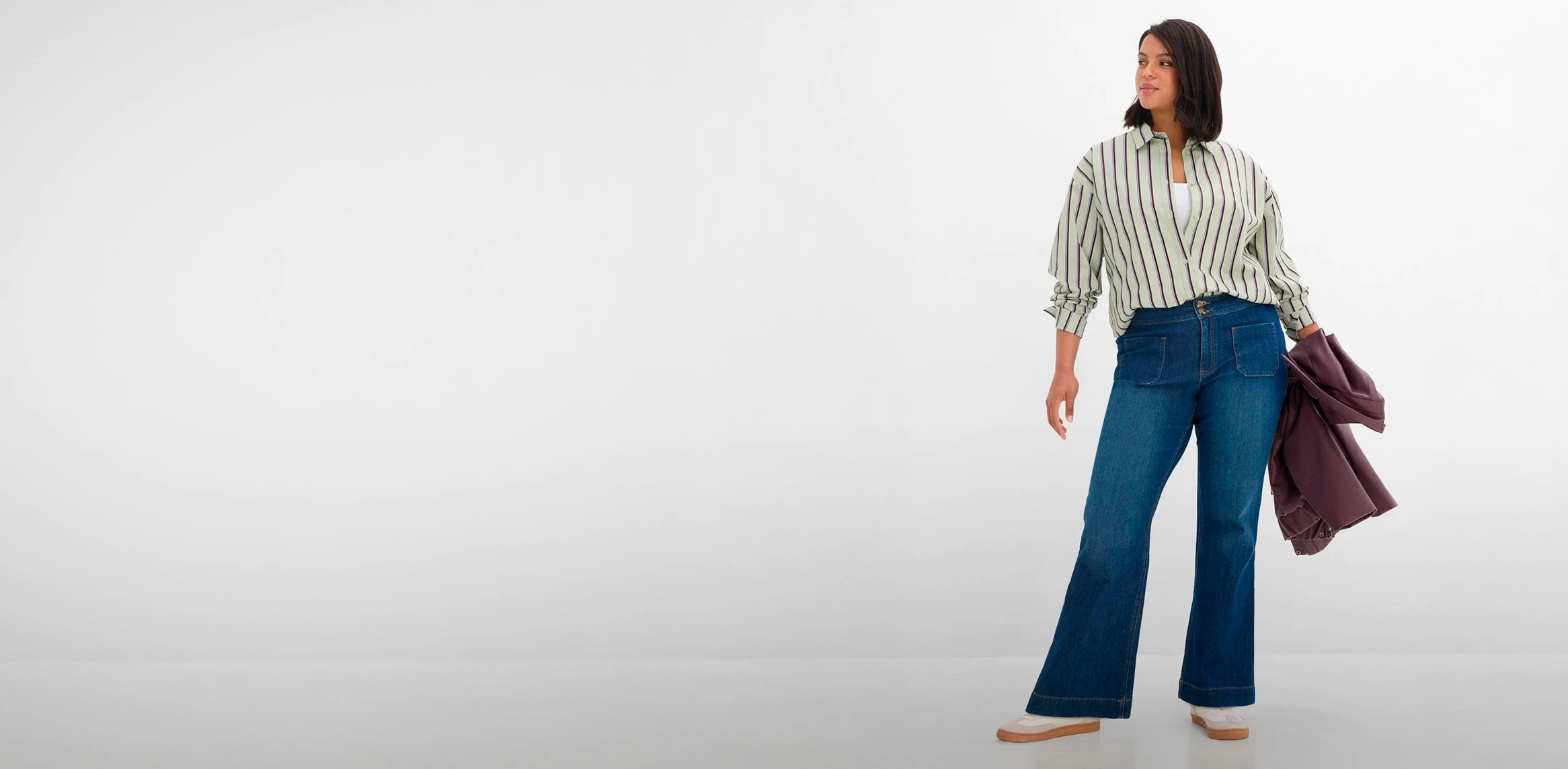 Ležérní outfit: pruhovaná košile, modré džíny s rozšířenými nohavicemi a moderní bunda.