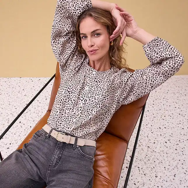 Puntíkovaná halenka s dlouhým rukávem v kombinaci s džínami a páskem.