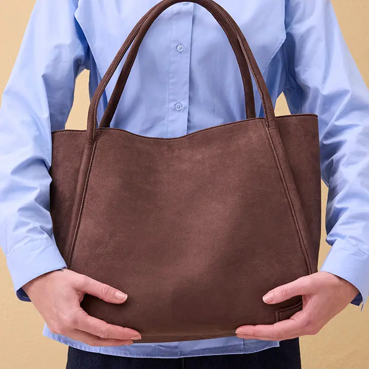 Světlemodrá halenka a hnědá kožená kabelka.