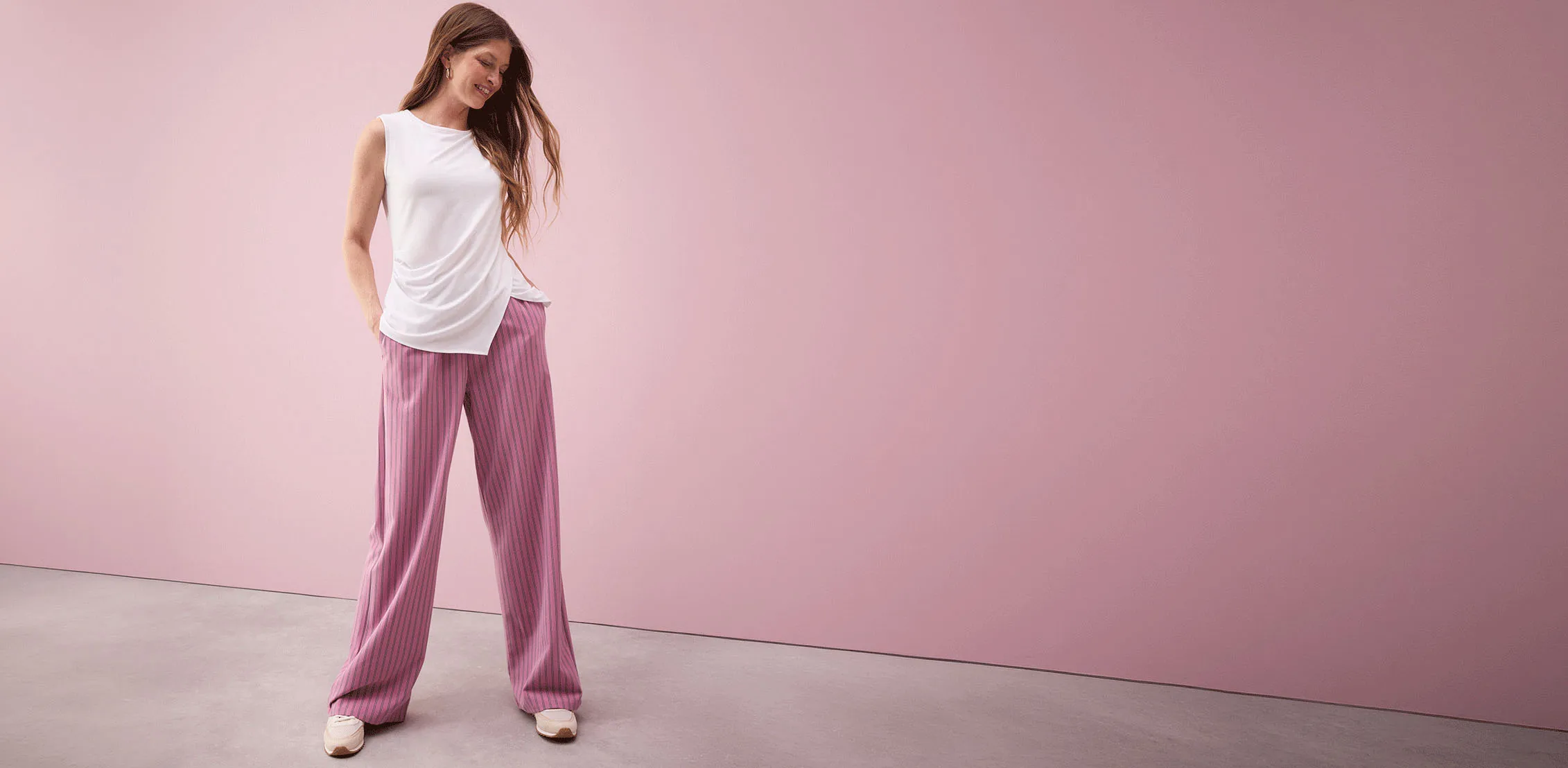Bílý top bez rukávů v kombinaci s růžovými pruhovanými kalhotami palazzo.