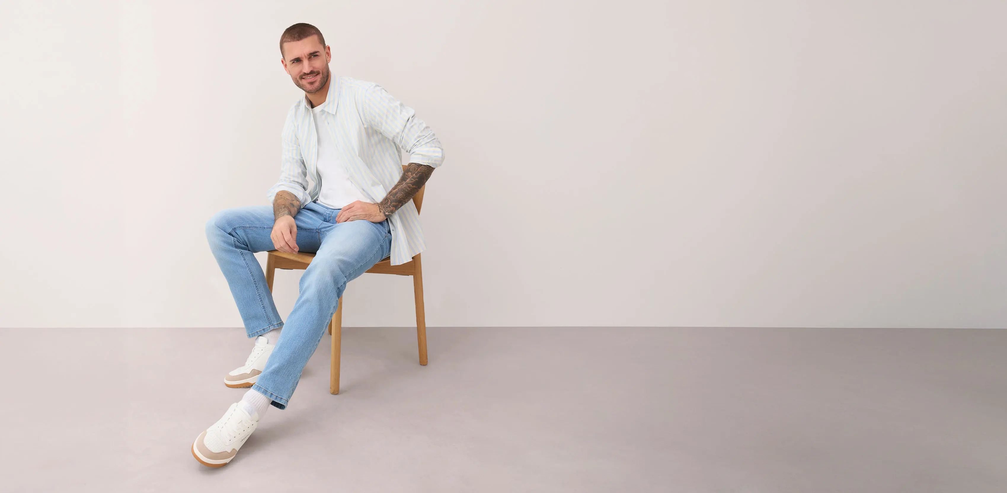 Bílá proužkovaná košile, světle modré džíny a bílé tenisky.