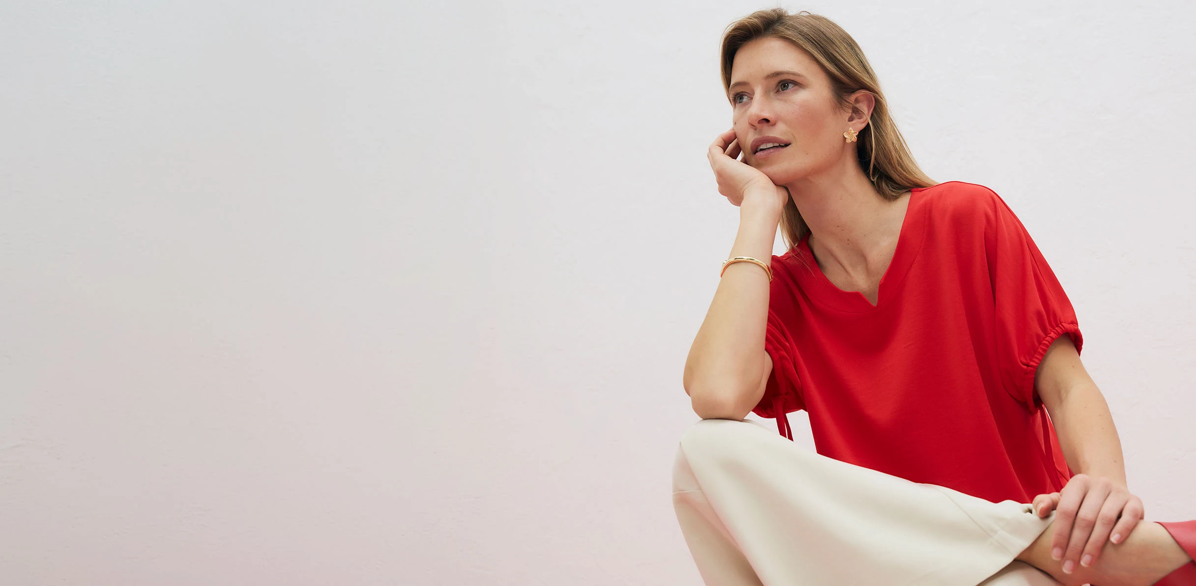 Elegantní červené tričko s výstřihem do V, zkombinované se světlými kalhotami.