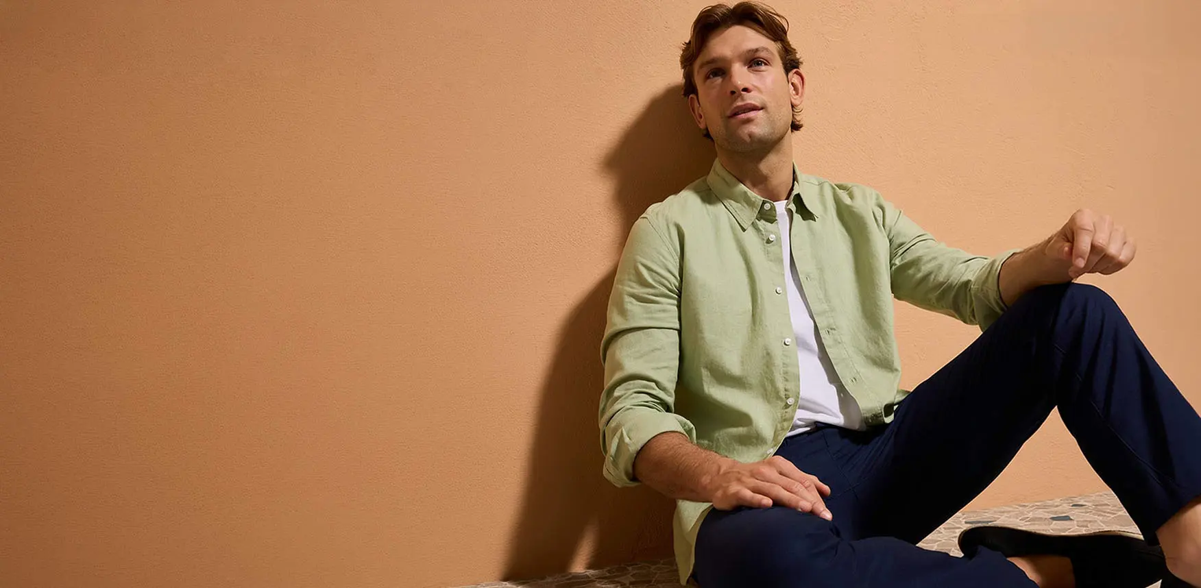 Pastelově zelená košile, tmavomodré kalhoty a ležérní boty.