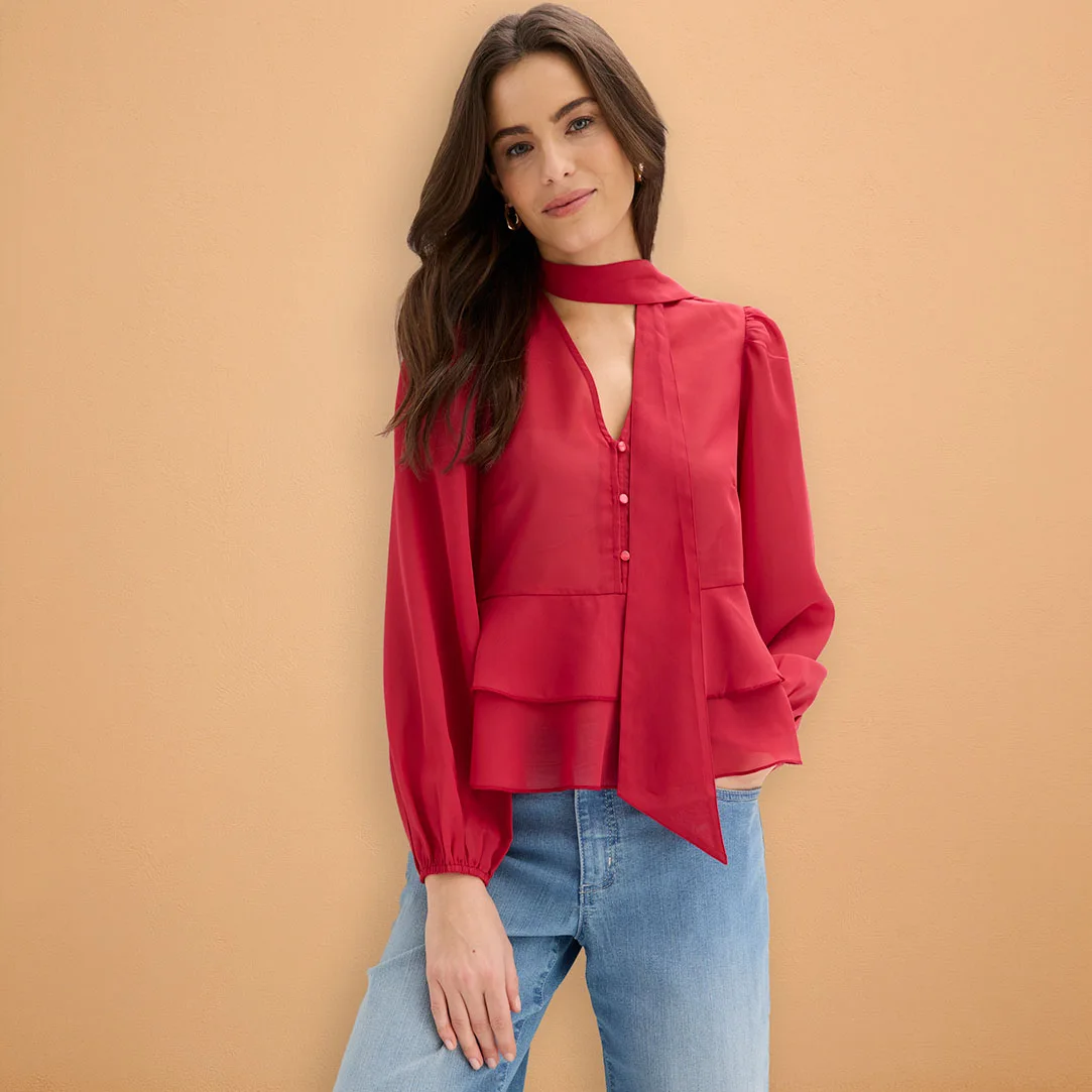 Červená halenka s dlouhým rukávem kombinovaná se světle modrými džínami.