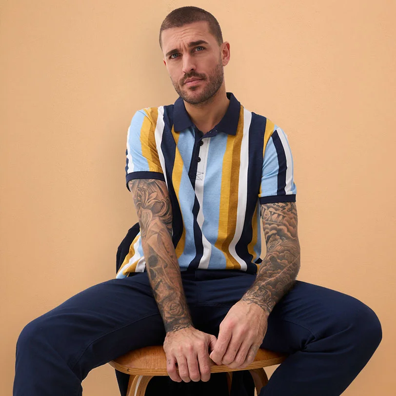 Tmavě modro-žluté pruhované polo tričko kombinované s tmavě modrými kalhotami.