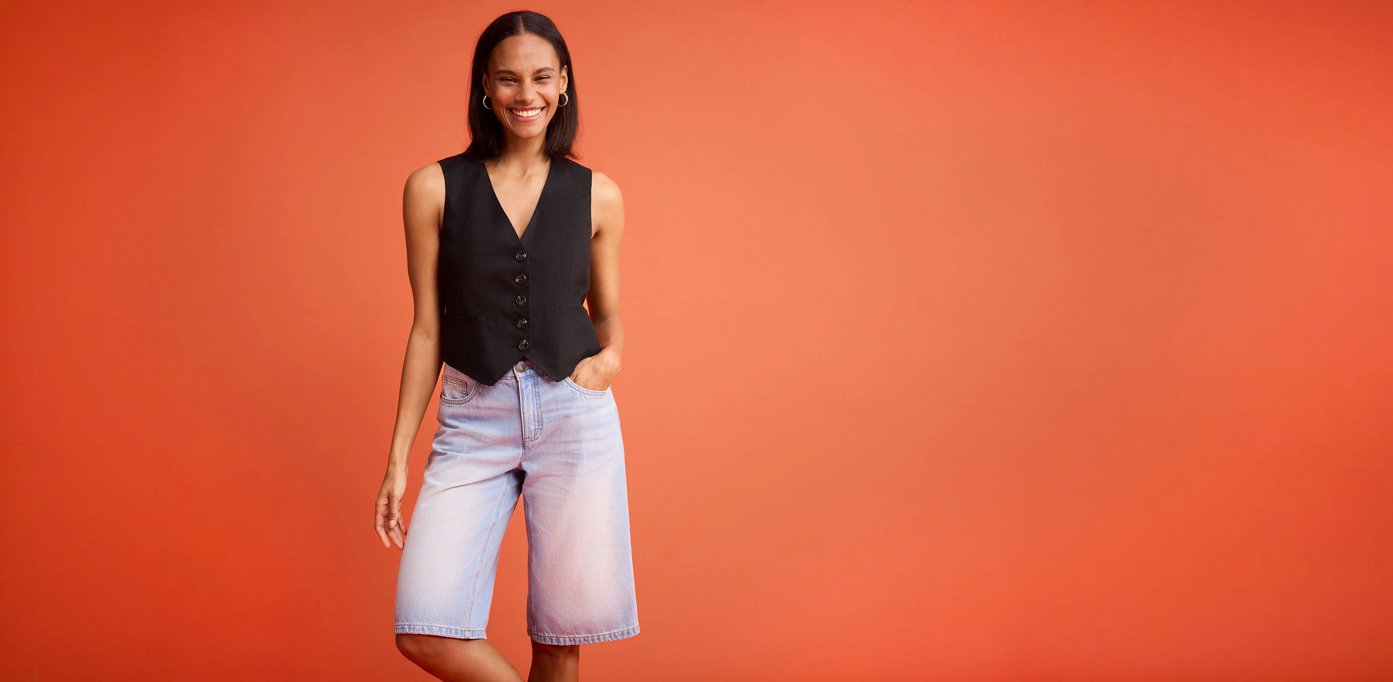 Černá vesta s knoflíky, v kombinaci se světle modrými džínovými šortkami.