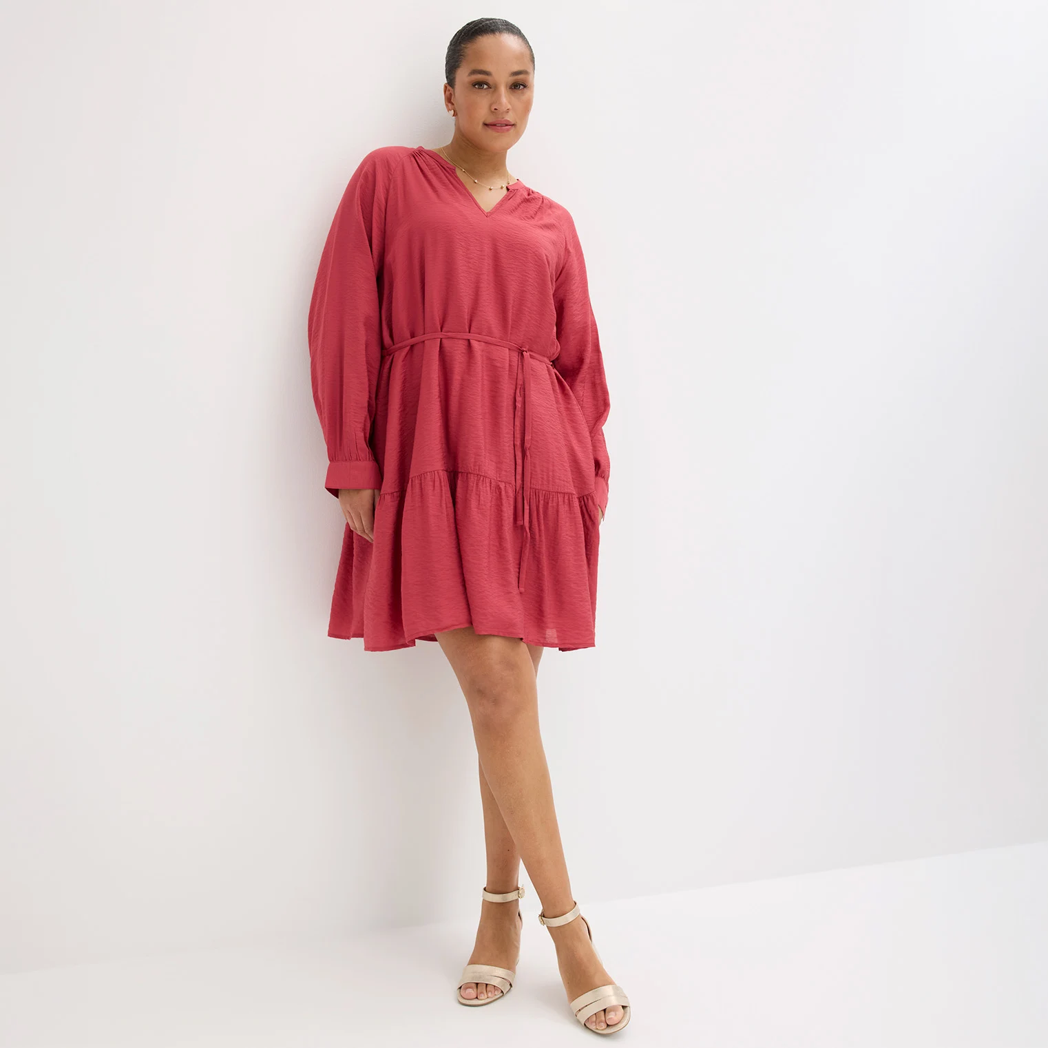 Elegantní červené šaty s dlouhým rukávem a bílé sandály na vysokém podpatku pro stylový outfit.