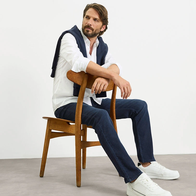 Stylový neformální outfit: bílá košile, modrý svetr, džíny a bílé tenisky.